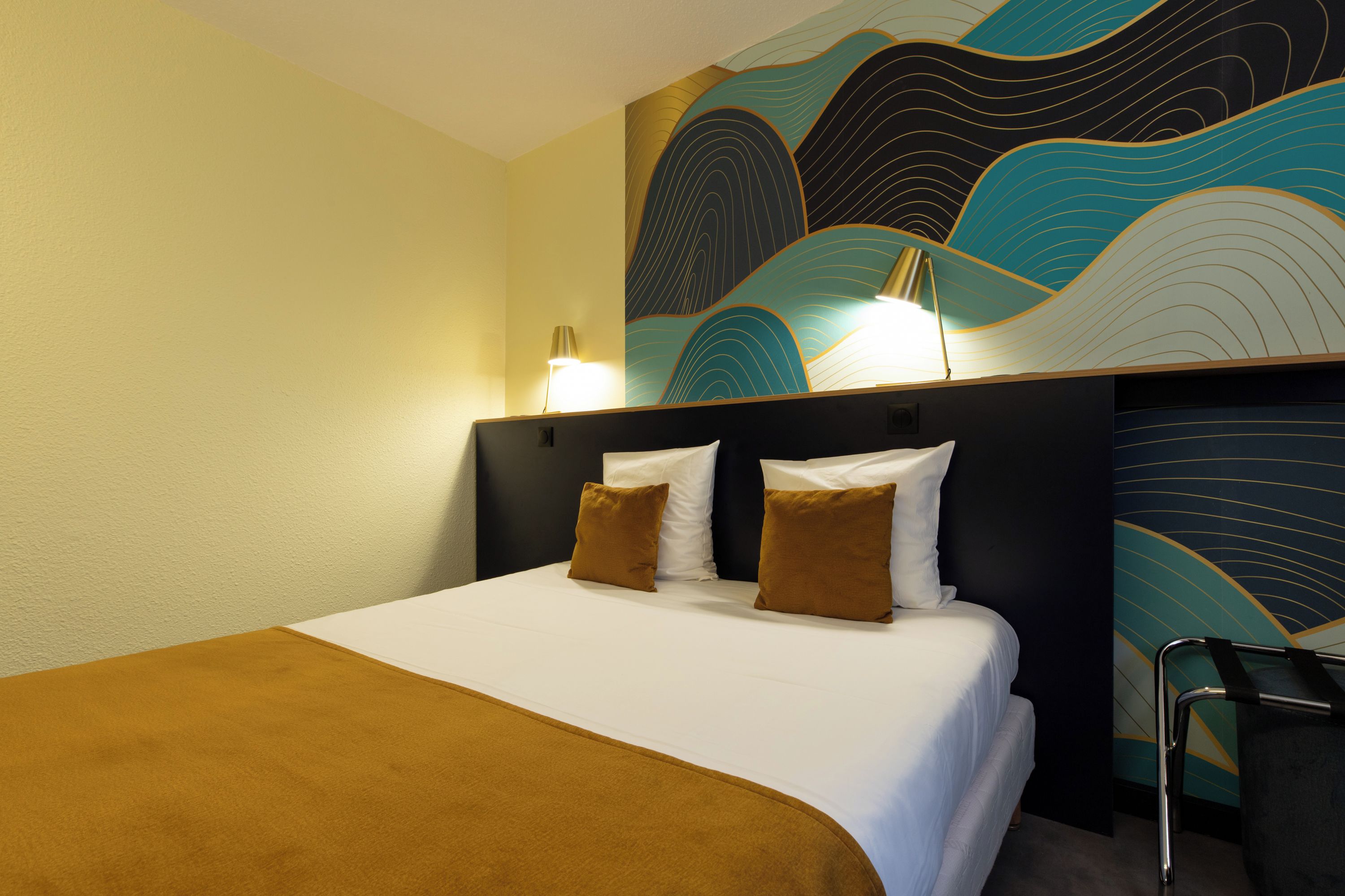 Hotelkamer met een bed, twee kussens, een hoofdbord, een muur met een golfpatroon en een stoel.