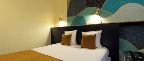 Habitación de hotel con cama, dos almohadas, cabecera, pared con diseño de ondas y una silla.