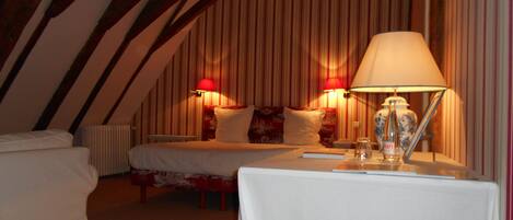 A cozy room with a bed, a table with a lamp, and two wall-mounted lamps.