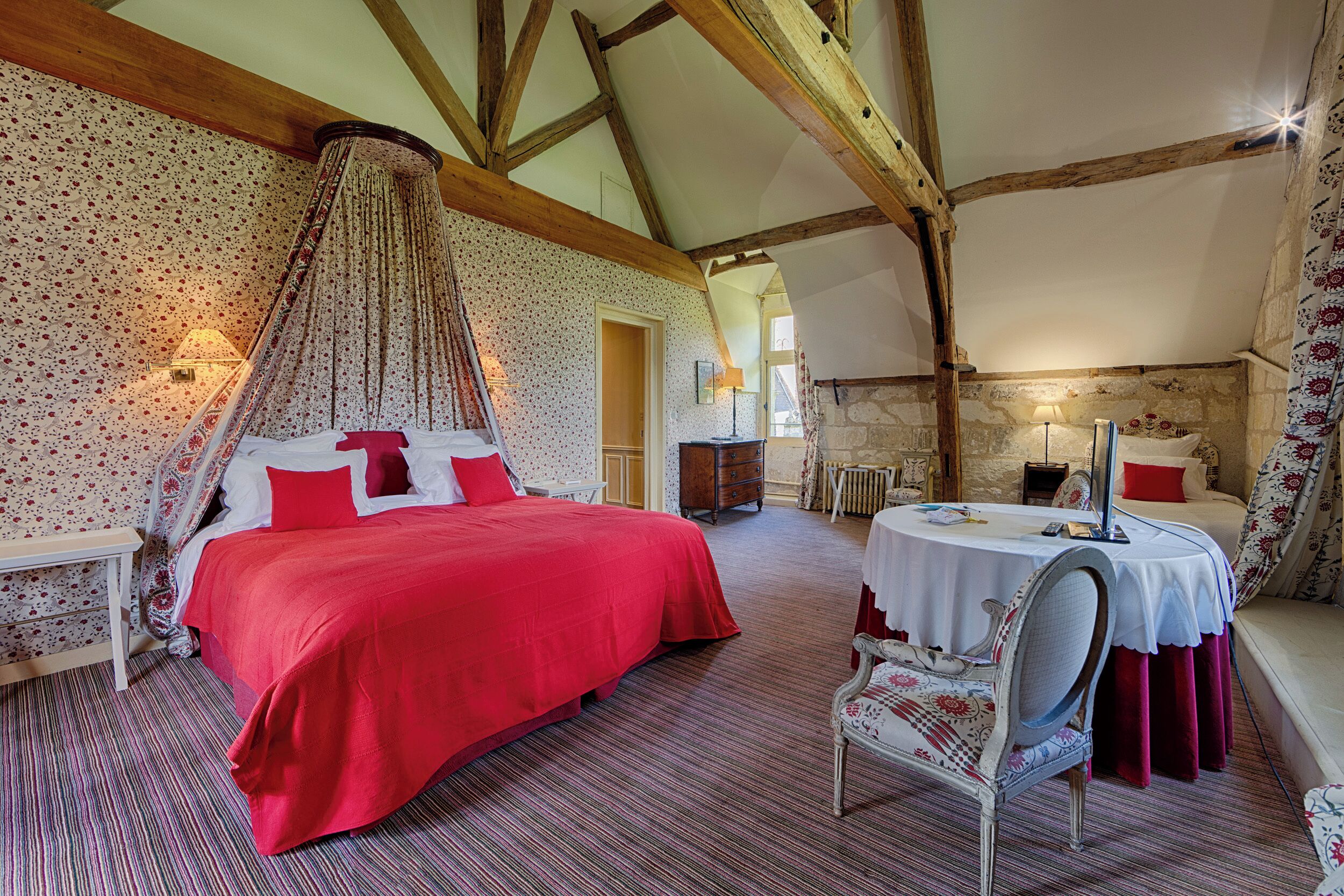 A bedroom with a large bed, a dining table, and a chair.