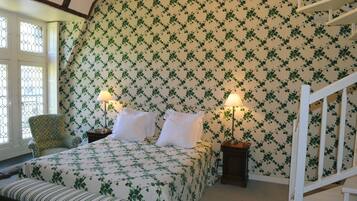 Une chambre avec un lit, deux tables de chevet, une chaise et un escalier blanc.