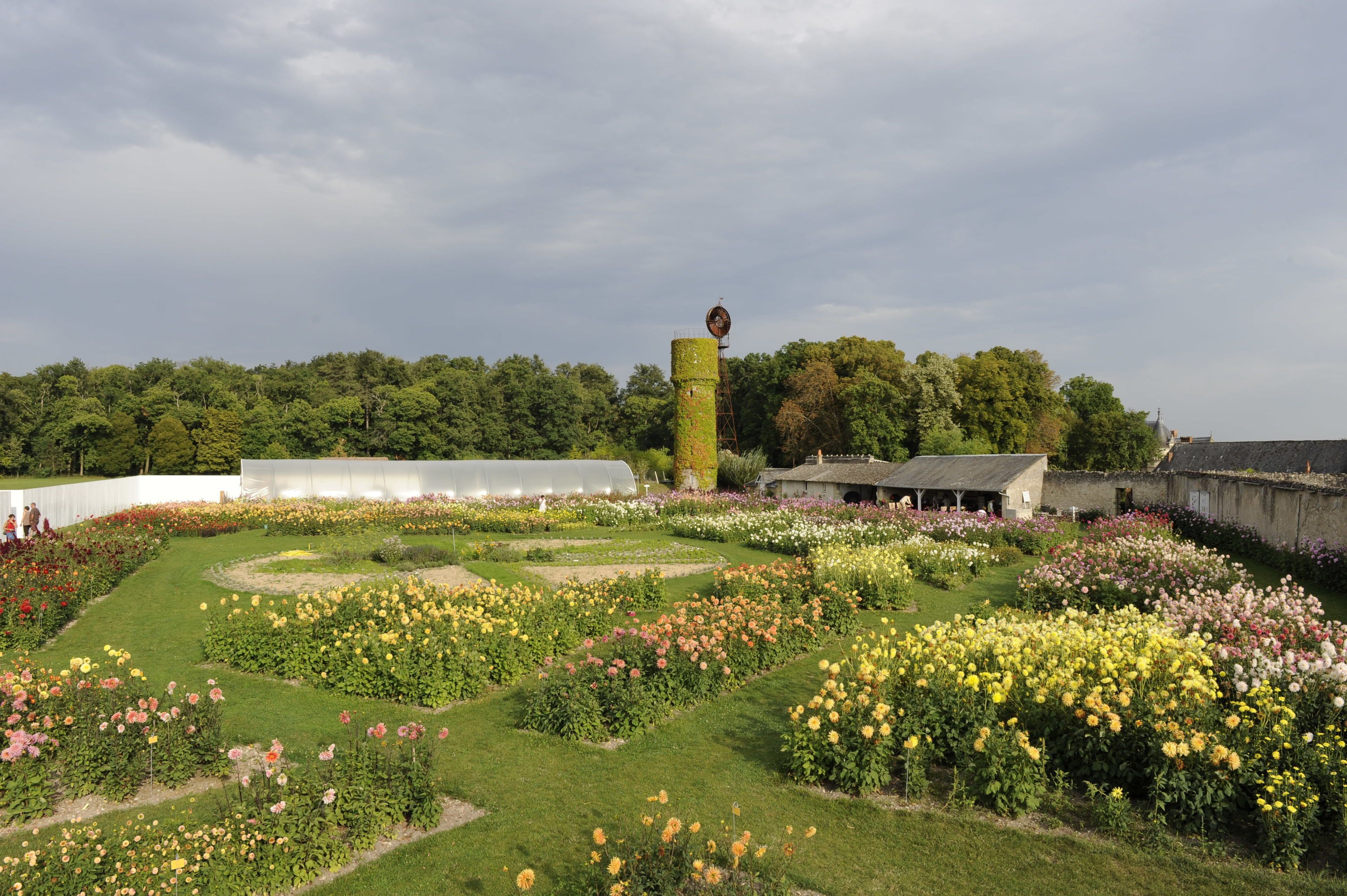 A garden with various flower beds and a tall tower structure.