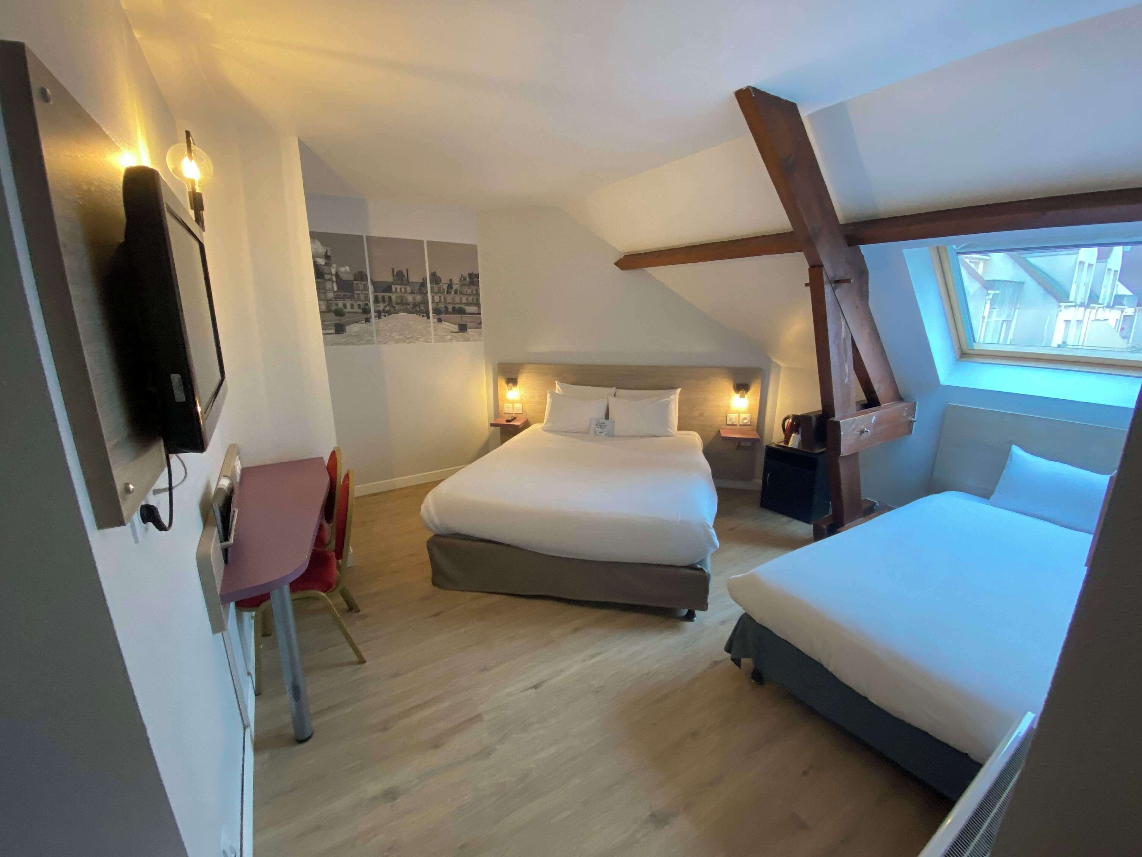 A bedroom with two beds, a desk, and a chair.