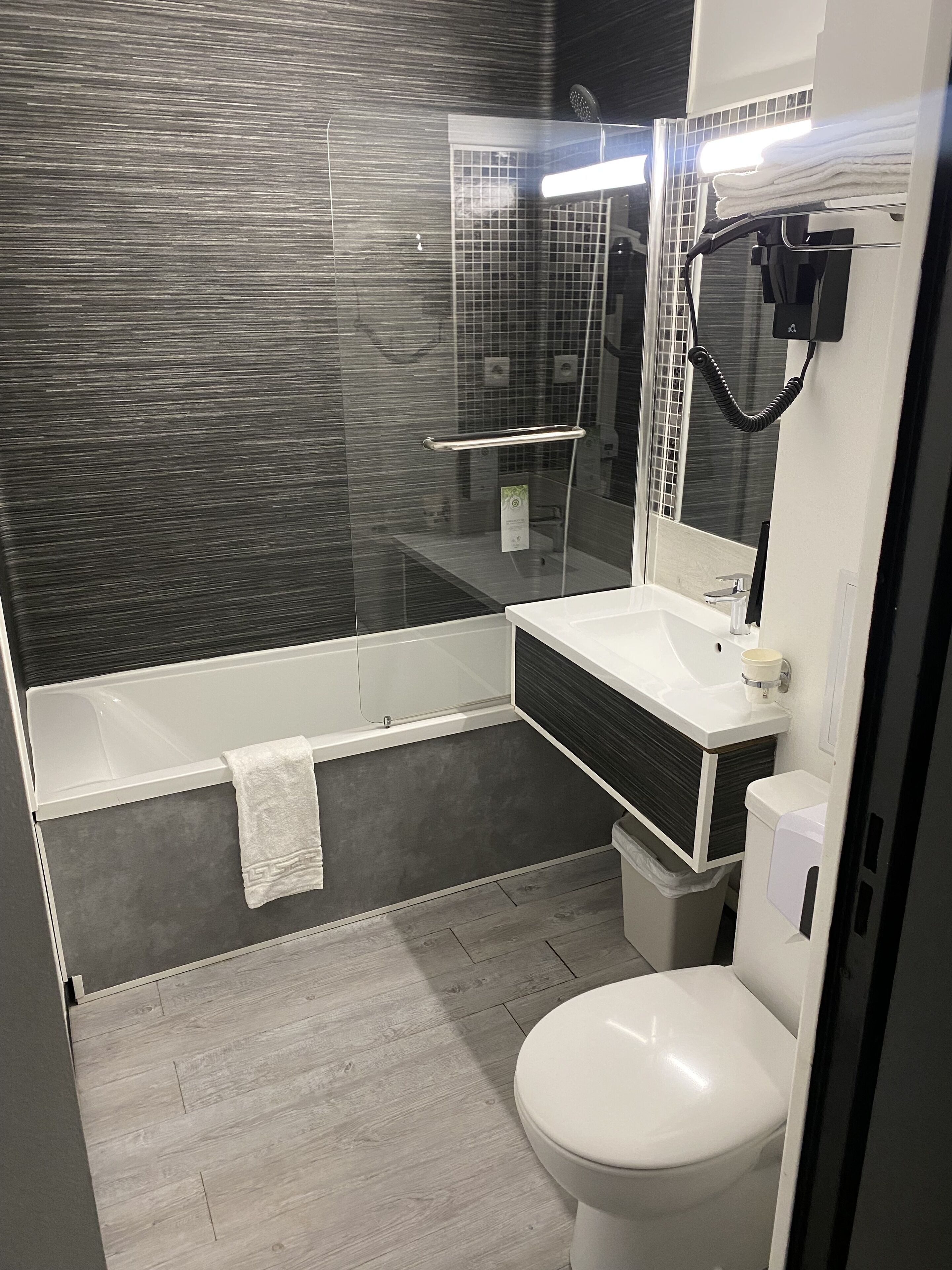 A modern bathroom with a glass-enclosed shower, a white sink, and a toilet.