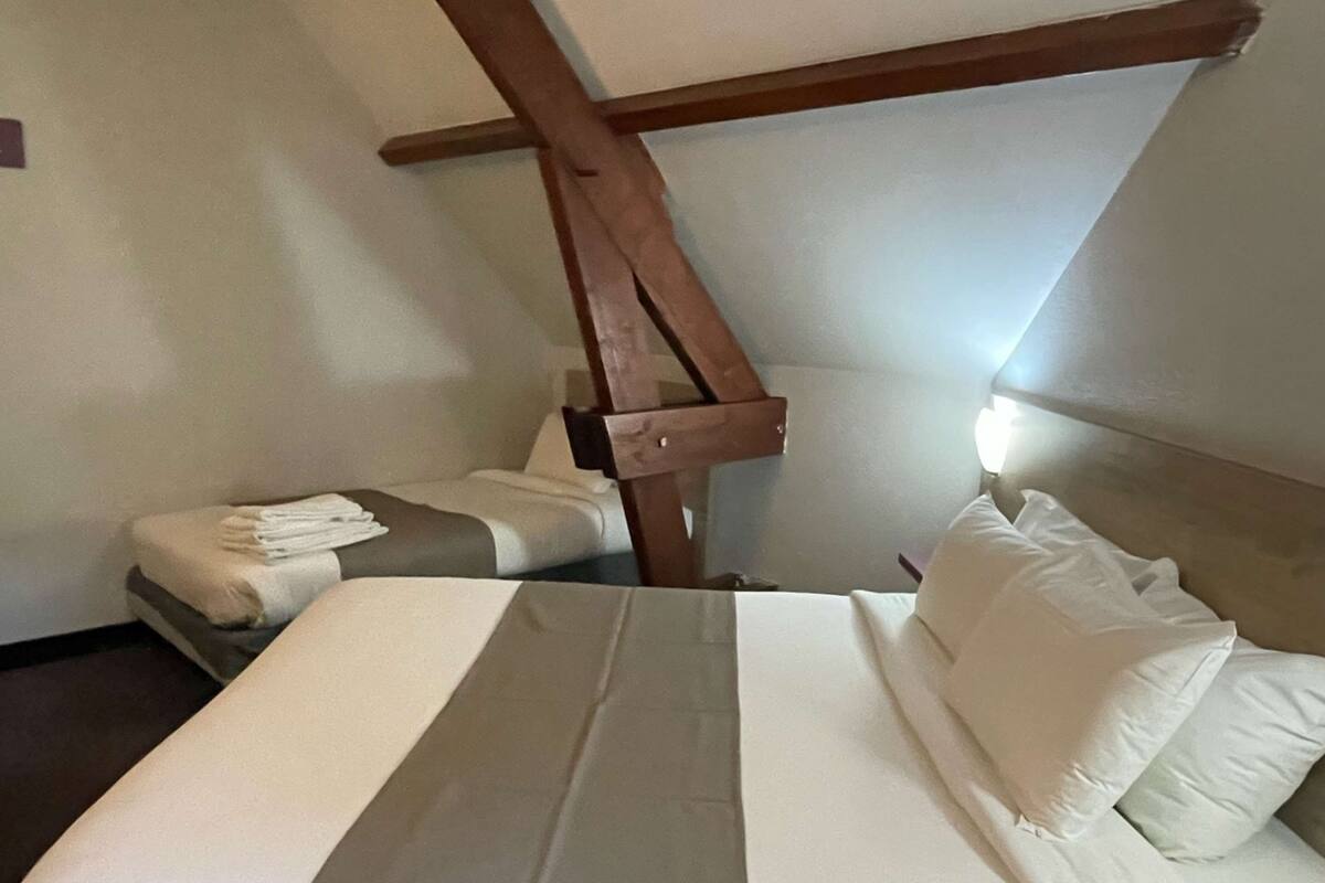 A hotel room with a bed, a wooden headboard, and a nightstand.