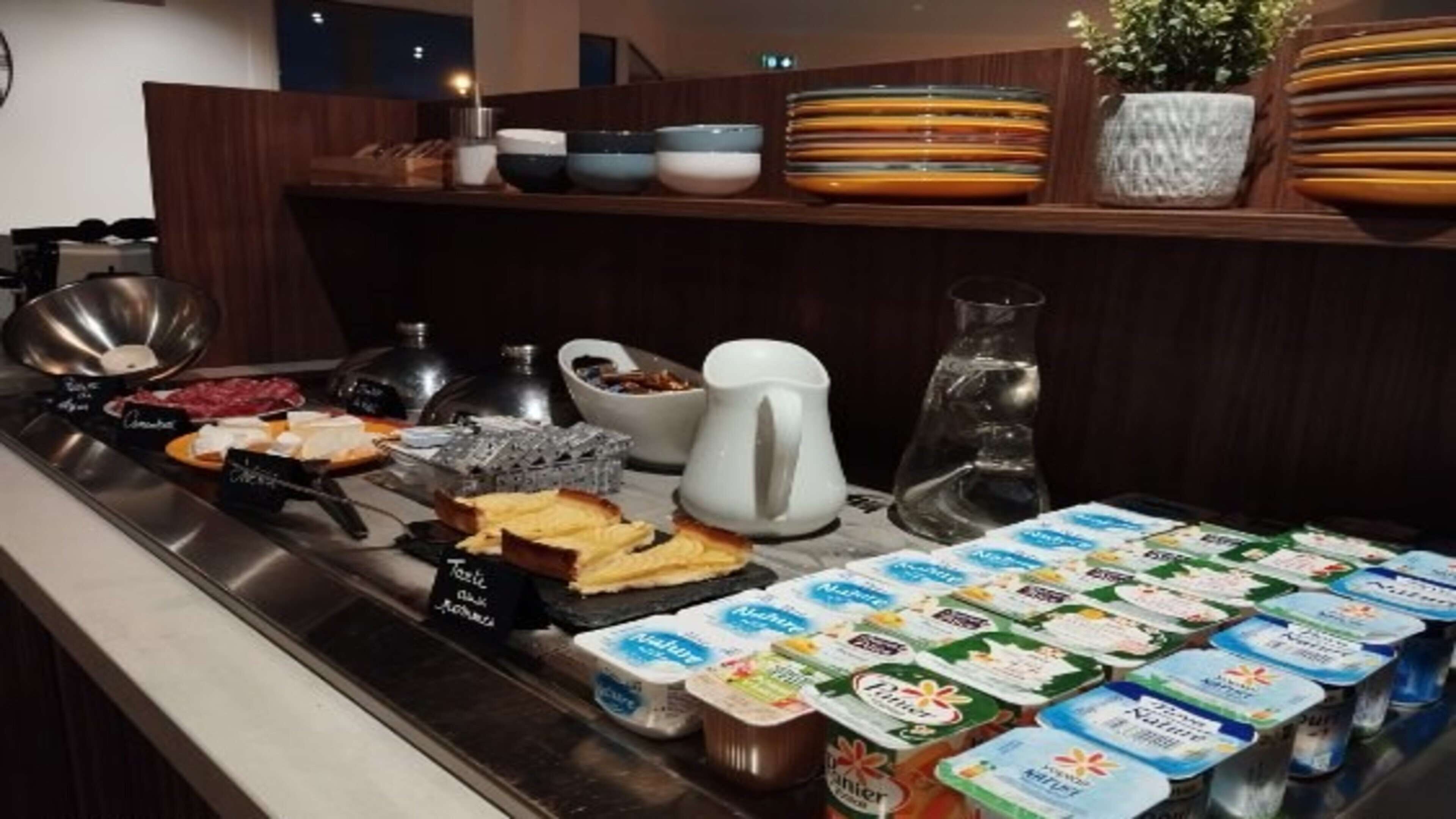 Montaje tipo bufé con diversos alimentos, incluyendo carnes, quesos y productos lácteos.