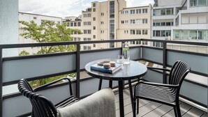 A balcony with a round table, two chairs, a book, a glass pitcher, and a glass. - Numa Berlin Kudamm (Berlin)