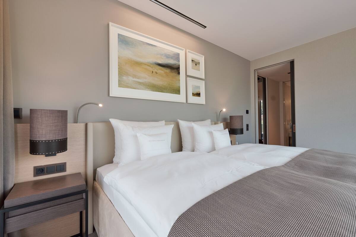 Et moderne hotelværelse med en stor seng, sengeborde og et kunstværk på væggen.