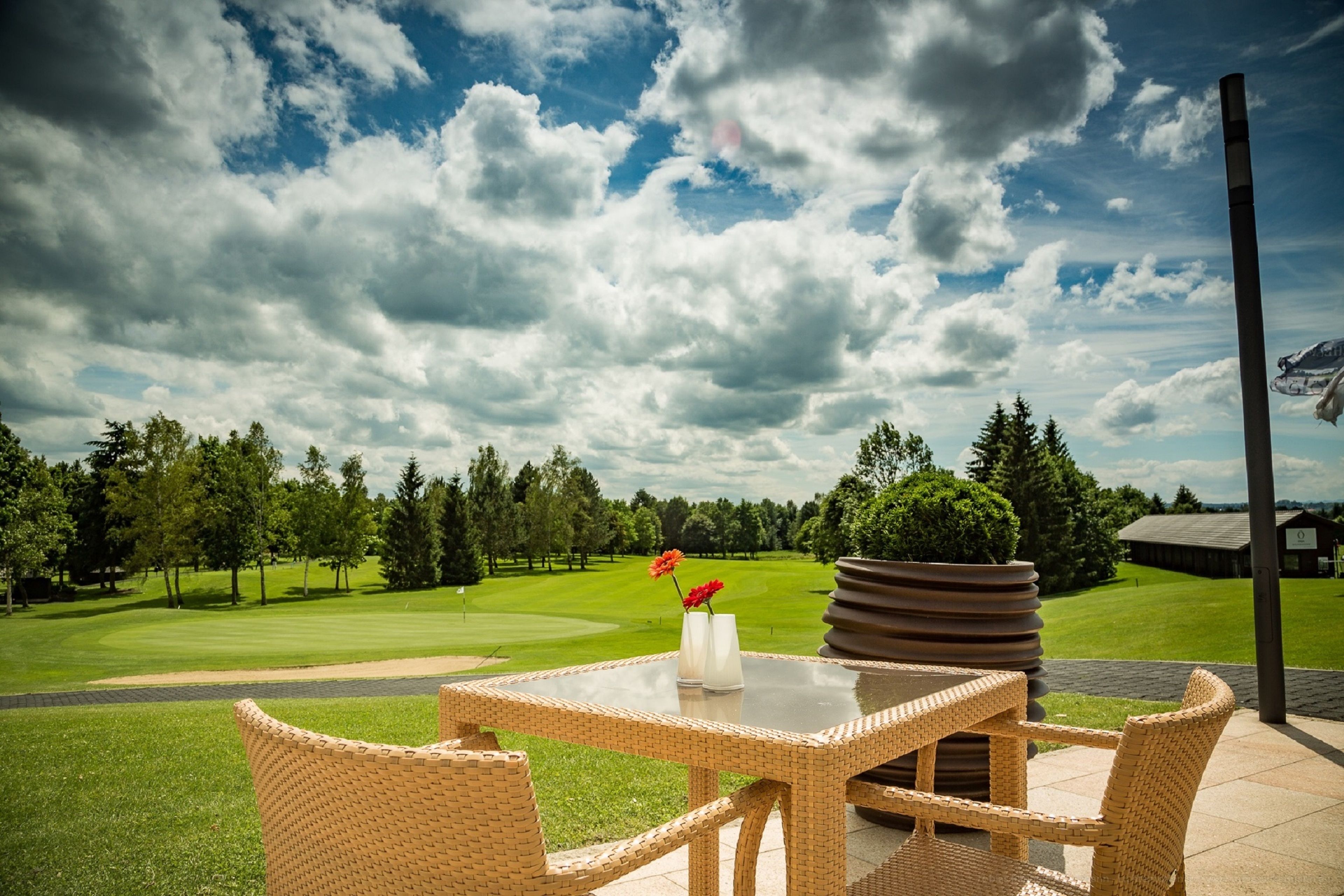 Ein Sitzbereich aus Rattangeflecht im Freien mit Blick auf einen Golfplatz.