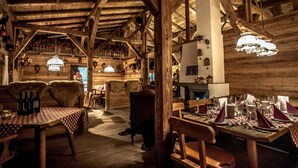 A rustic wooden interior with a high ceiling, wooden beams, and a dining area set up with tables and chairs. - Severin*s Resort & Spa Öschberghof (Donaueschingen)