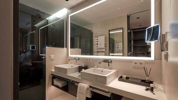 A modern bathroom with two sinks, a large mirror, and a glass shower enclosure.