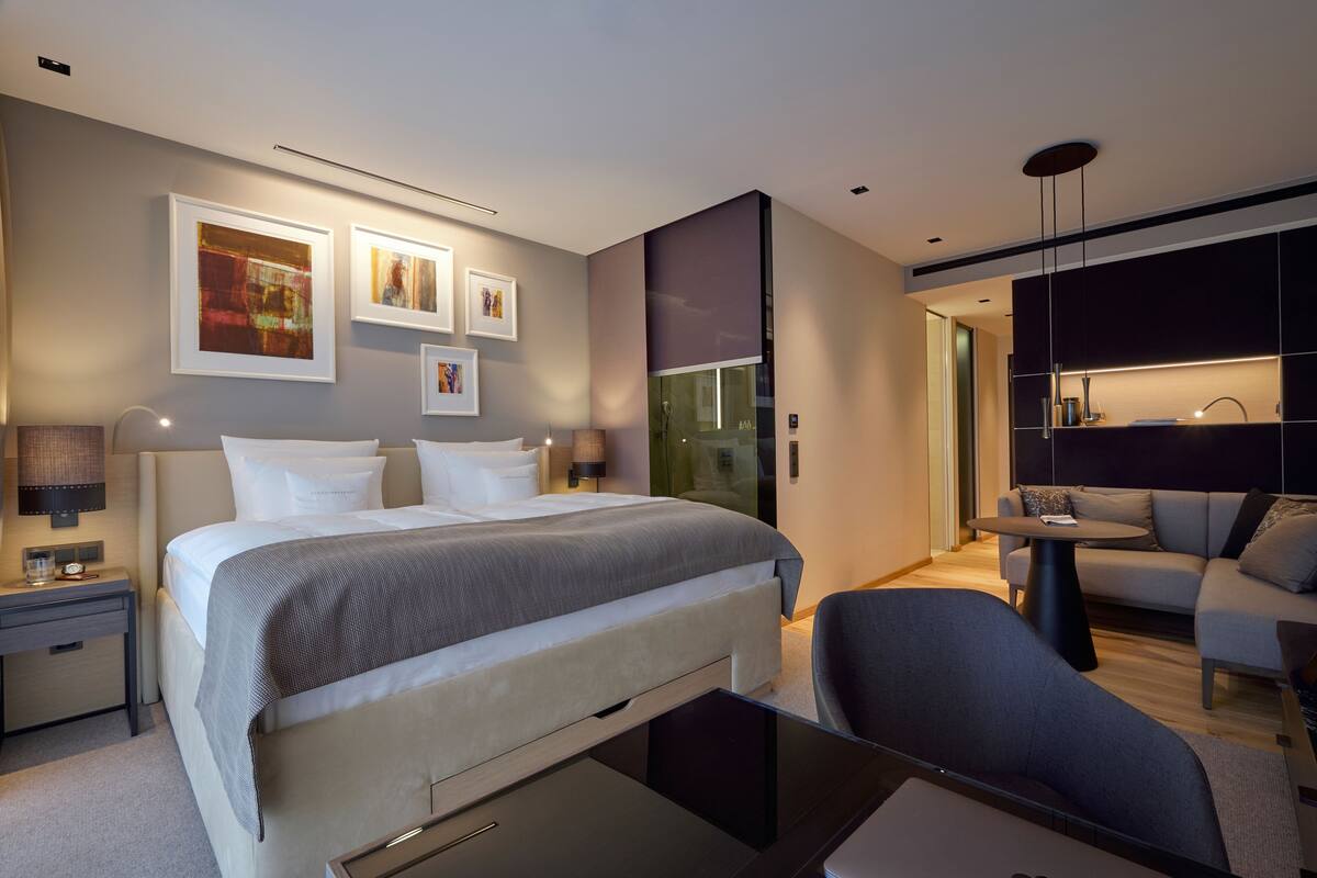 Et moderne hotelværelse med en stor seng, et skrivebord, en sofa og et lille bord.