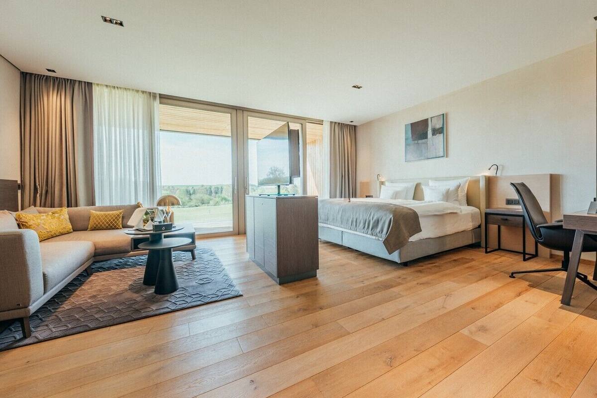 Et moderne hotelværelse med sofa, seng, skrivebord og et stort vindue.