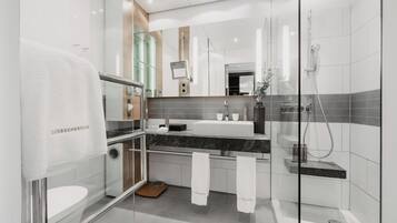 A modern bathroom with a glass shower enclosure, a white sink, and a marble countertop.