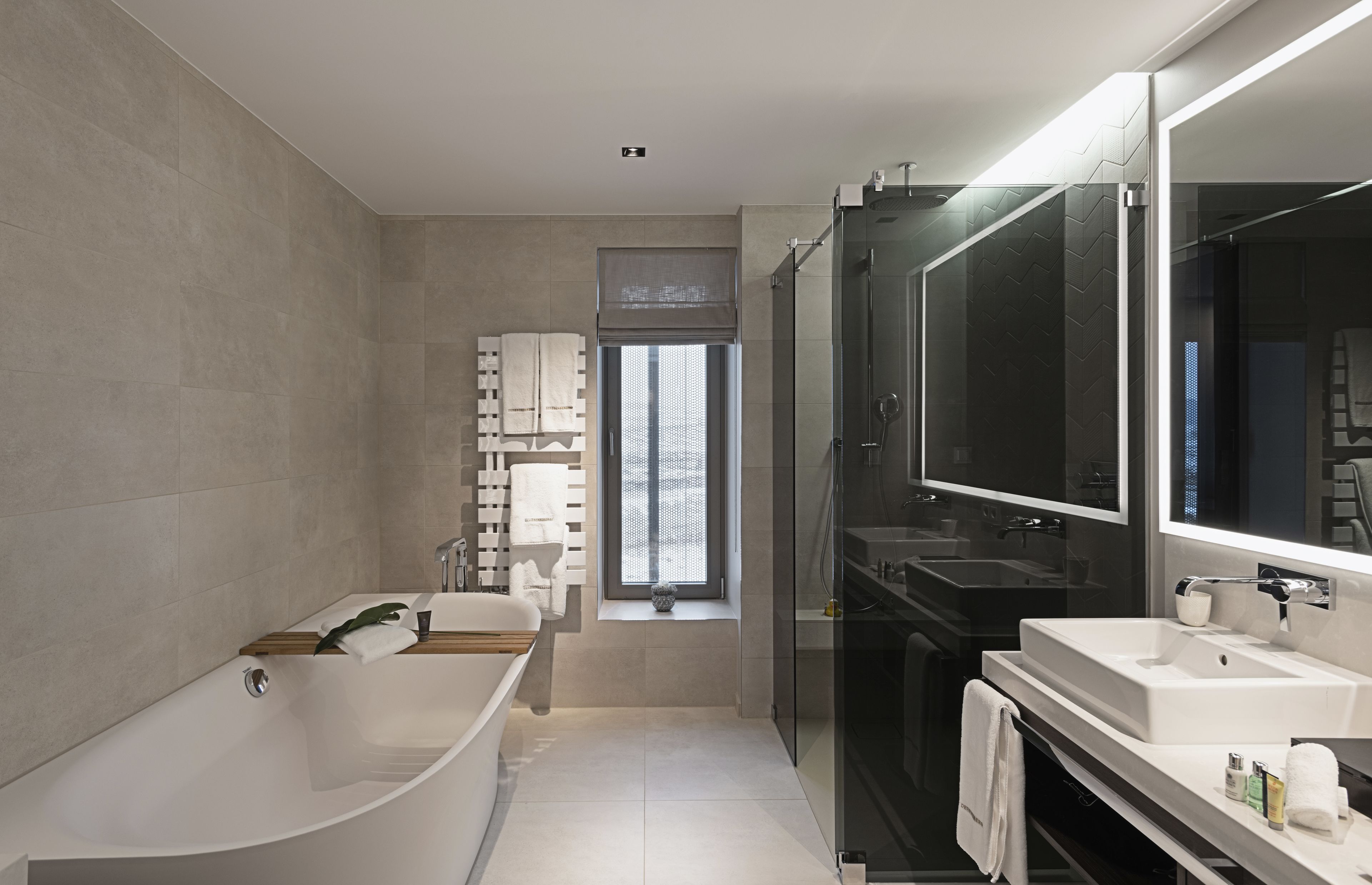 Un baño moderno con una bañera independiente, un espejo grande y una ducha con mampara de vidrio.