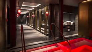 A modern hotel corridor with a red-lit reception area, a glass-enclosed spa, and a visible towel rack. - Severin*s Resort & Spa Öschberghof (Donaueschingen)