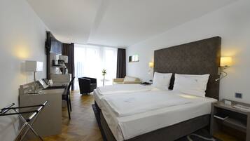 A hotel room with a large bed, a desk, a chair, and a TV.