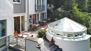A modern building with a glass conservatory, outdoor seating, and a staircase leading to an upper level. - Hotel Caroline Mathilde (Celle)