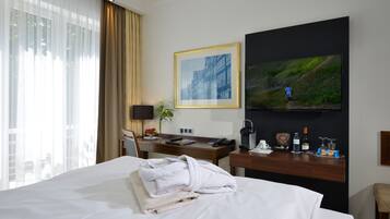 Une chambre d’hôtel avec un lit, un bureau, une télévision et une fenêtre avec des rideaux.