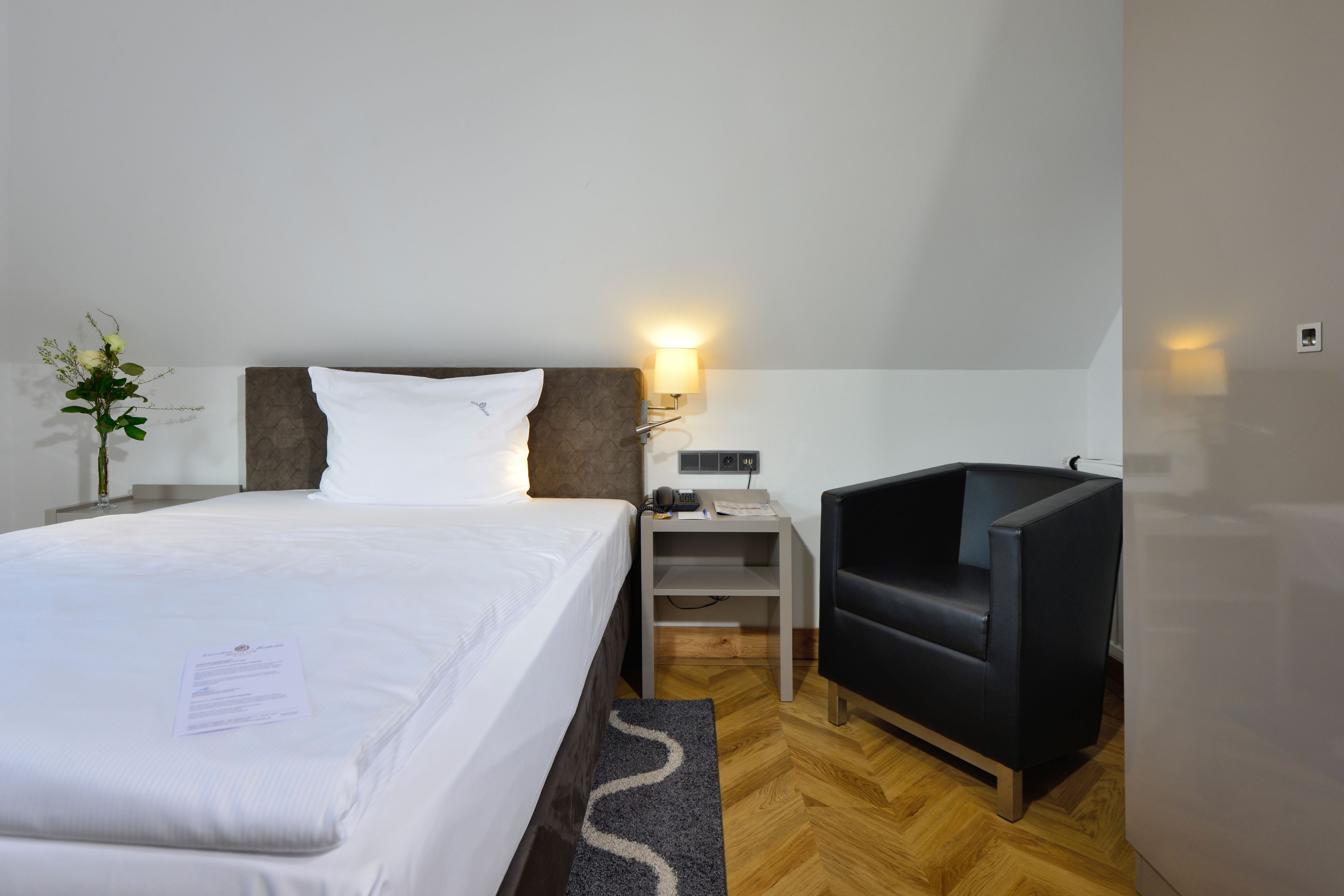 Ett hotellrum med en säng, ett skrivbord, en stol och ett nattduksbord.