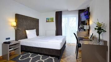 Ein modernes Hotelzimmer mit einem großen Bett, einem Schreibtisch, einem Fernseher und einer kleinen Arbeitsfläche.