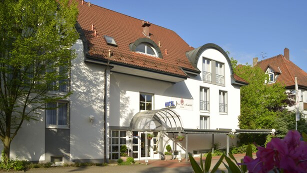 A white hotel with a red-tiled roof, a covered entrance, and a sign indicating it is a hotel. - Hotel Caroline Mathilde (Celle)