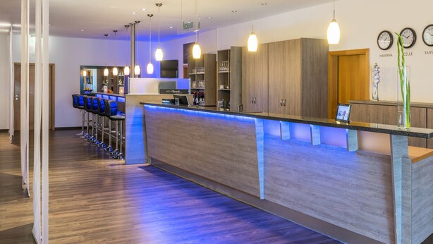 A modern hotel lobby with a reception desk, bar area, and seating. - Hesse Hotel Celle (Celle)
