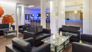 A modern lobby with leather sofas, glass tables, and a reception desk. - Hesse Hotel Celle (Celle)