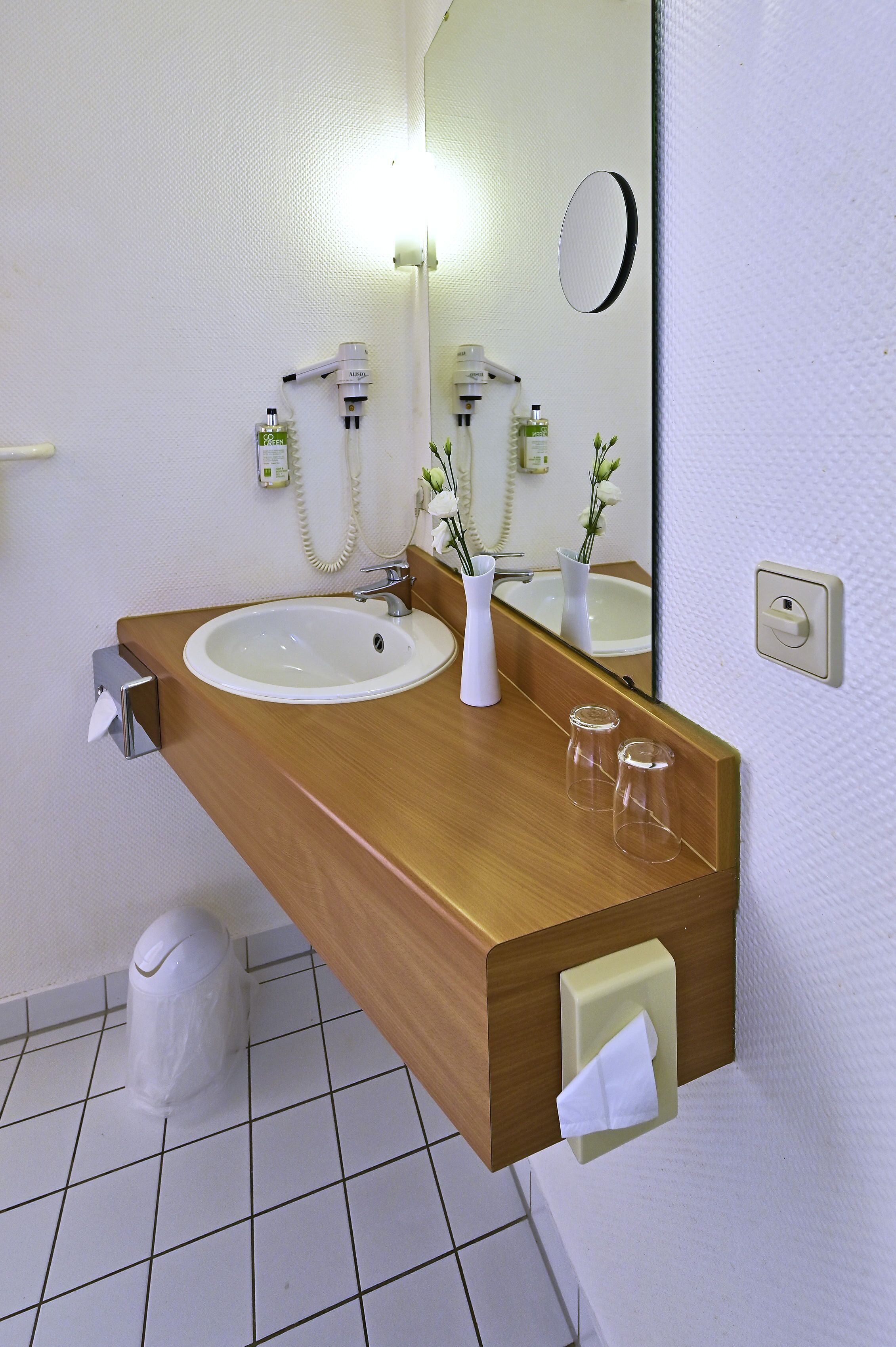 Un baño moderno con dos lavamanos, un espejo y un dispensador de toallas.
