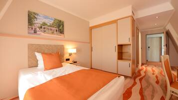 A hotel room with a bed, a nightstand, a lamp, a wardrobe, and a chair.