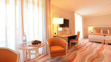 A hotel room with a bed, a desk with a chair, a small table with a chair, and a TV on the wall.