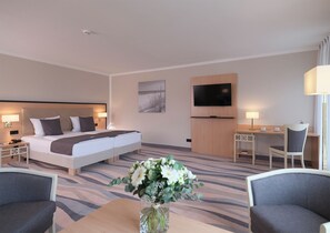 A hotel room with a bed, a desk, a TV, and a chair. - TOP CountryLine Seehotel Großherzog Ostseebad Boltenhagen (Boltenhagen)