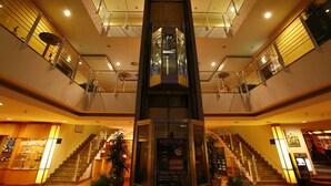 A modern hotel interior with a central elevator, multiple floors, and a staircase. - TOP CountryLine Seehotel Großherzog Ostseebad Boltenhagen (Boltenhagen)