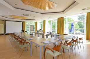 A conference room with long tables, chairs, and a projector screen.