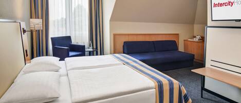 A hotel room with a bed, a desk, a chair, and a TV.