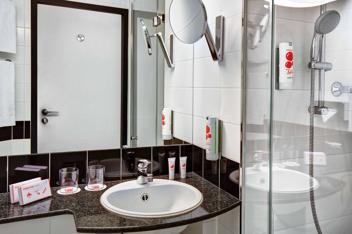 Ein modernes Badezimmer mit Waschbecken, Spiegel und einer Duschkabine.