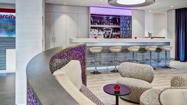 Un área de bar moderna con un diseño de asientos curvo, una barra y un letrero de neón.