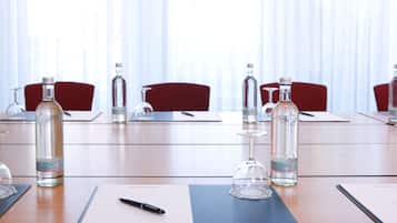 A conference room with a long table, red chairs, water bottles, wine glasses, and a pen on a notepad labeled "InterCityHotel".