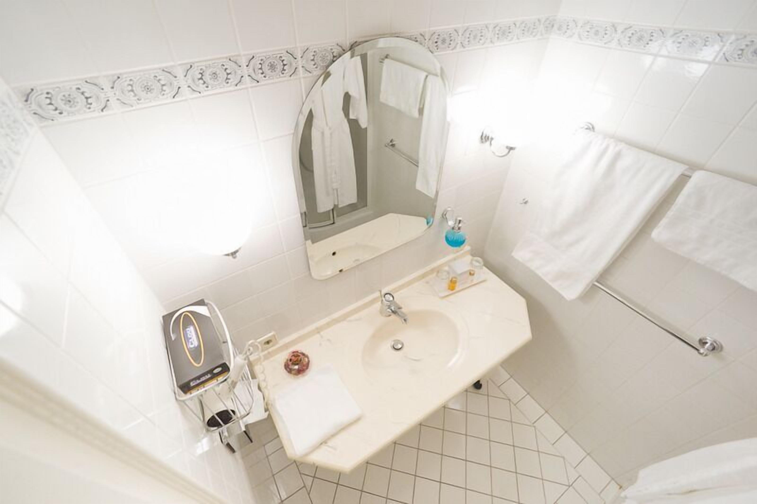 A bathroom with a sink, mirror, towel rack, and a shower area.