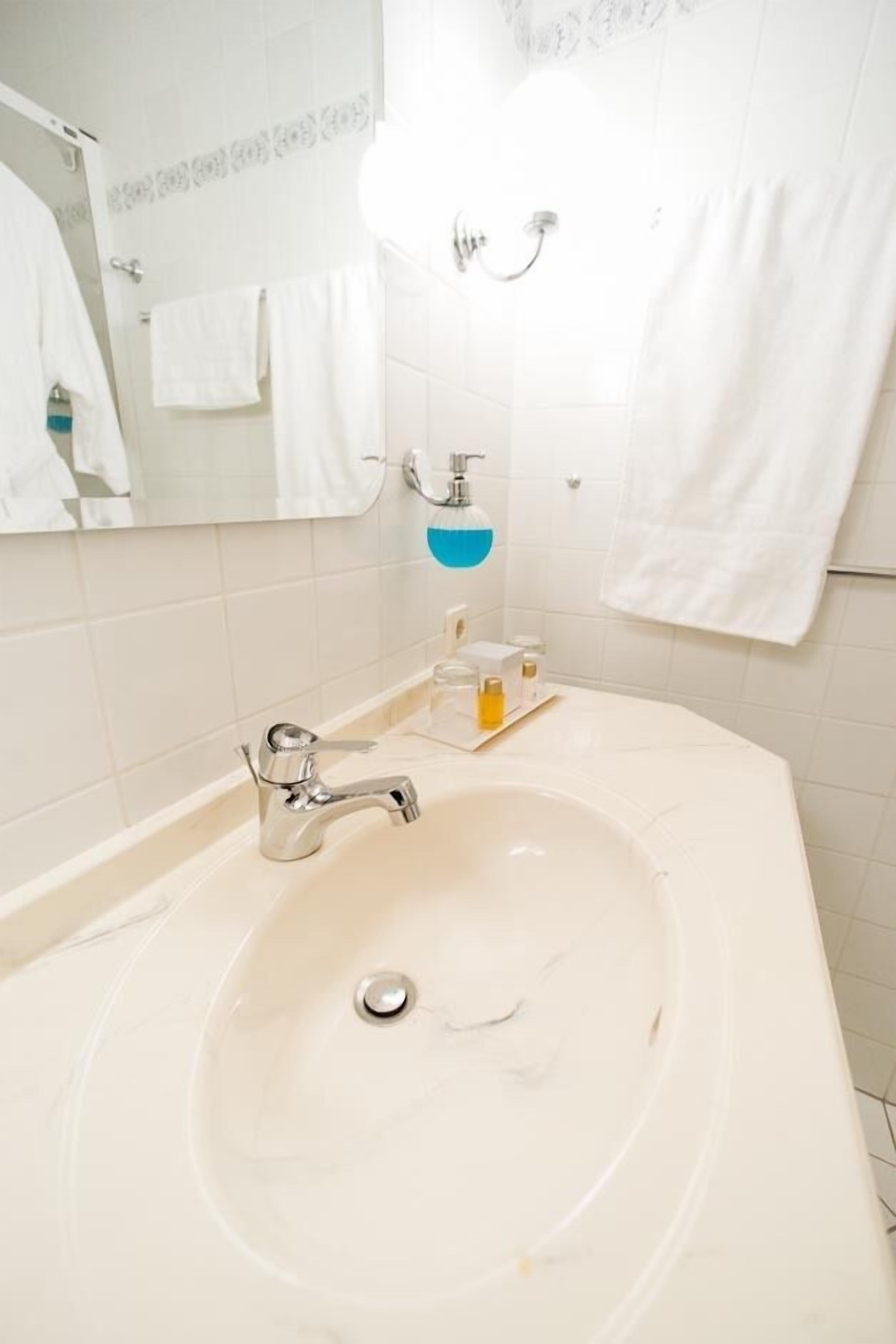 Un baño con un lavabo grande de color blanco, un espejo y un perchero para toallas.