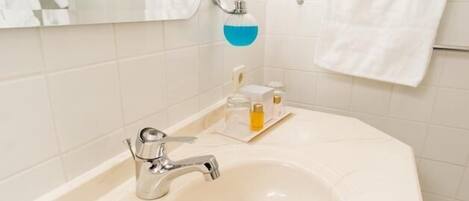 Un baño con un lavabo grande de color blanco, un espejo y un perchero para toallas.