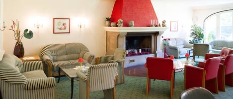 Una sala de estar con muebles a rayas, una chimenea y una pared de acento roja.