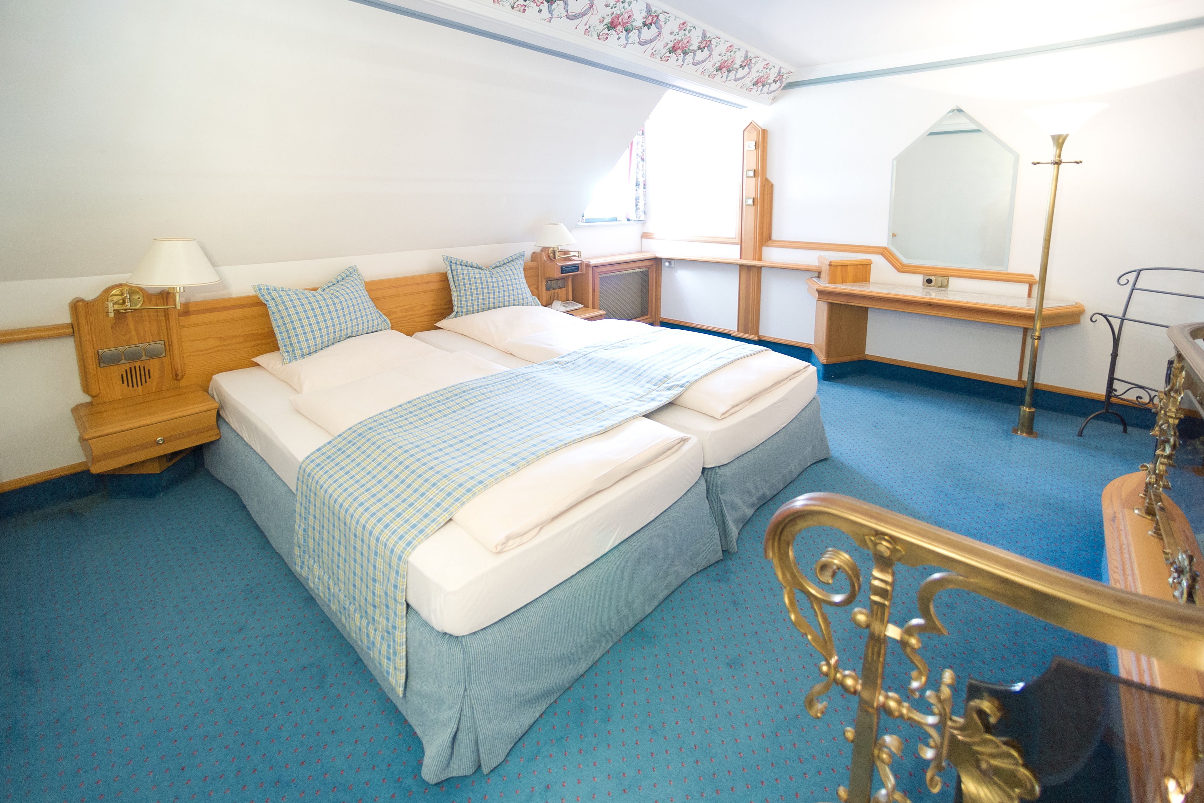 A bedroom with a large bed, wooden headboard, bedside tables with lamps, a dresser, and a mirror.