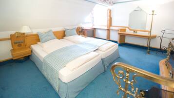 A bedroom with a large bed, wooden headboard, bedside tables with lamps, a dresser, and a mirror.