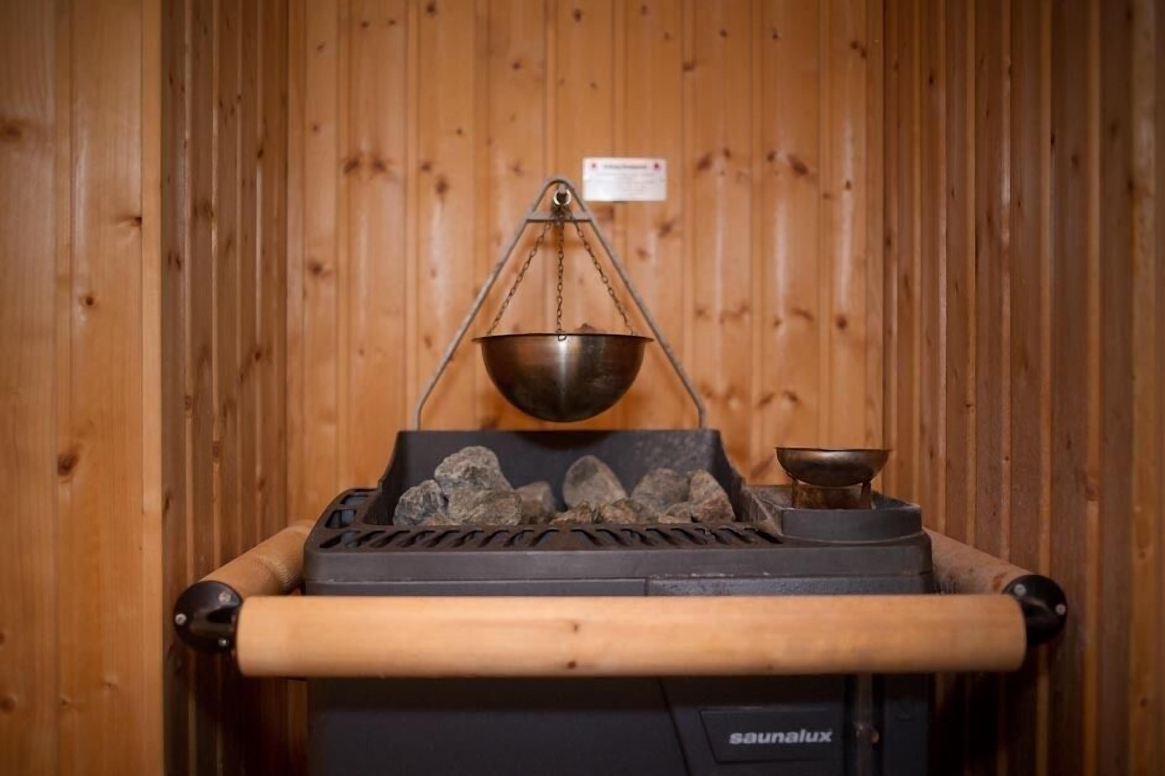 En sauna med træpaneler, en metalkar og en varmelegeme.