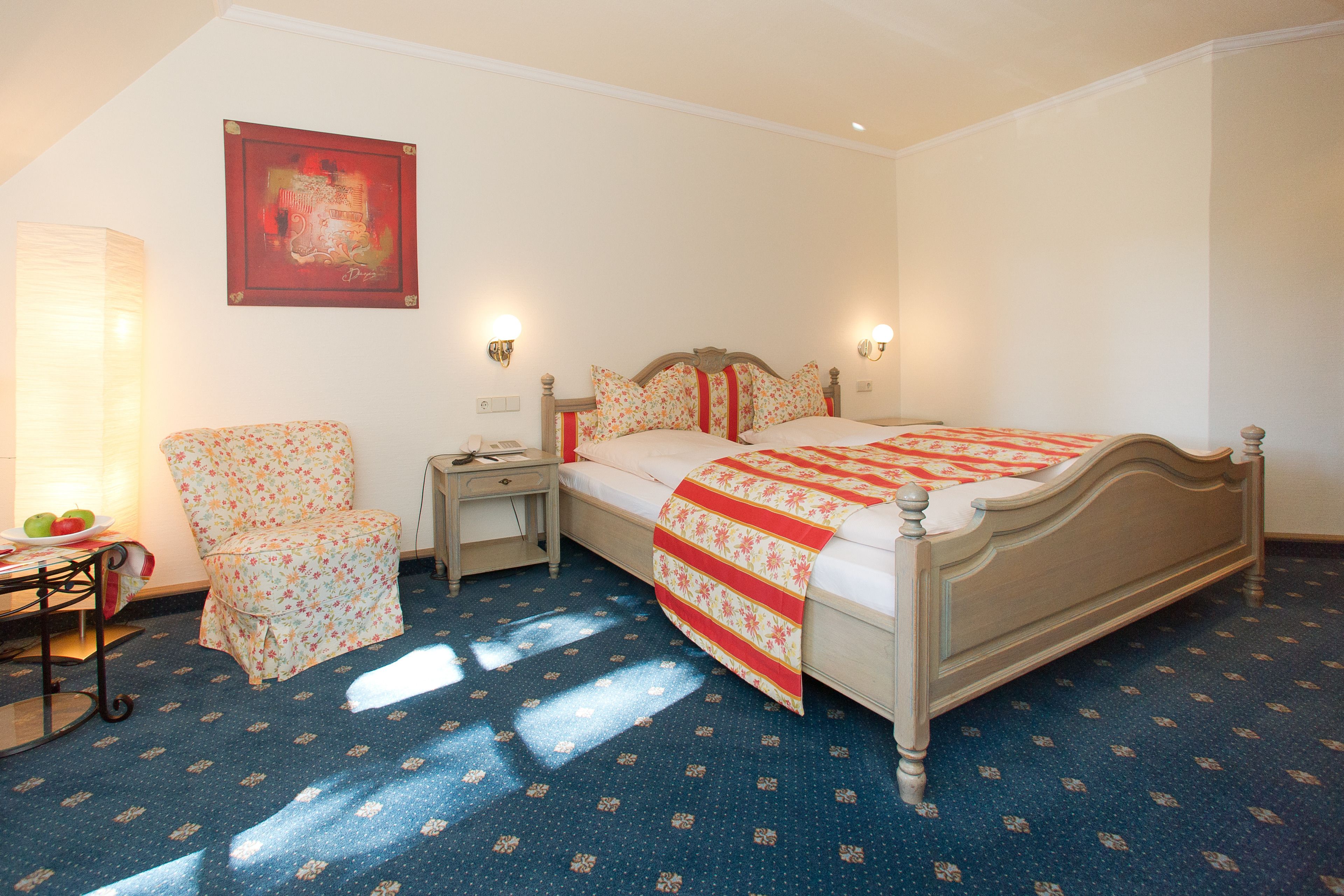 Ein Schlafzimmer mit einem Bett, einem Sessel, einem Nachttisch und einer Lampe.