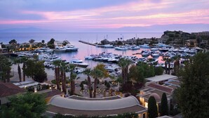 A marina with numerous yachts docked, surrounded by buildings and palm trees. - Porto Sani (Kassandra)