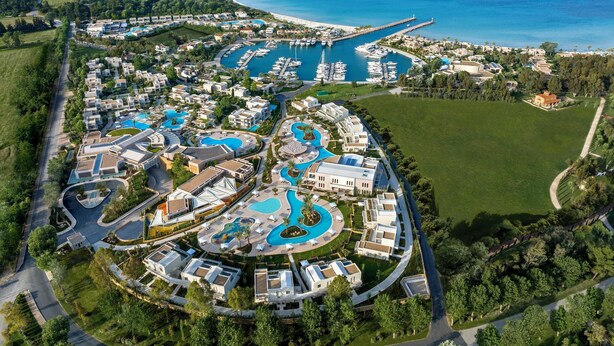 An aerial view of a resort with multiple swimming pools, a marina with boats, and a coastal backdrop. - Porto Sani (Kassandra)