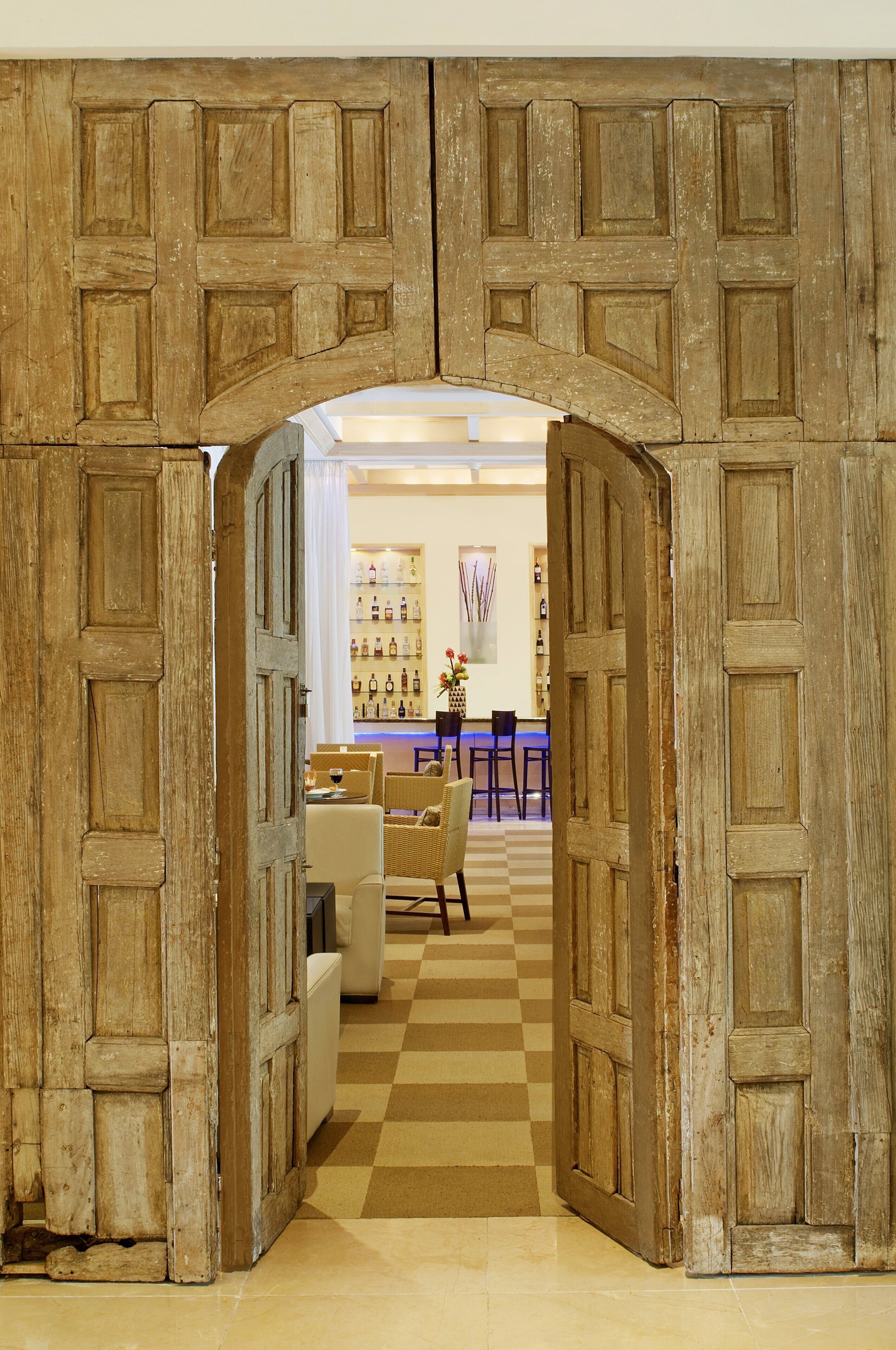 A doorway leading to a bar area with seating and a display of bottles.