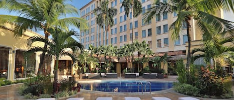 A hotel pool area with lounge chairs and palm trees.